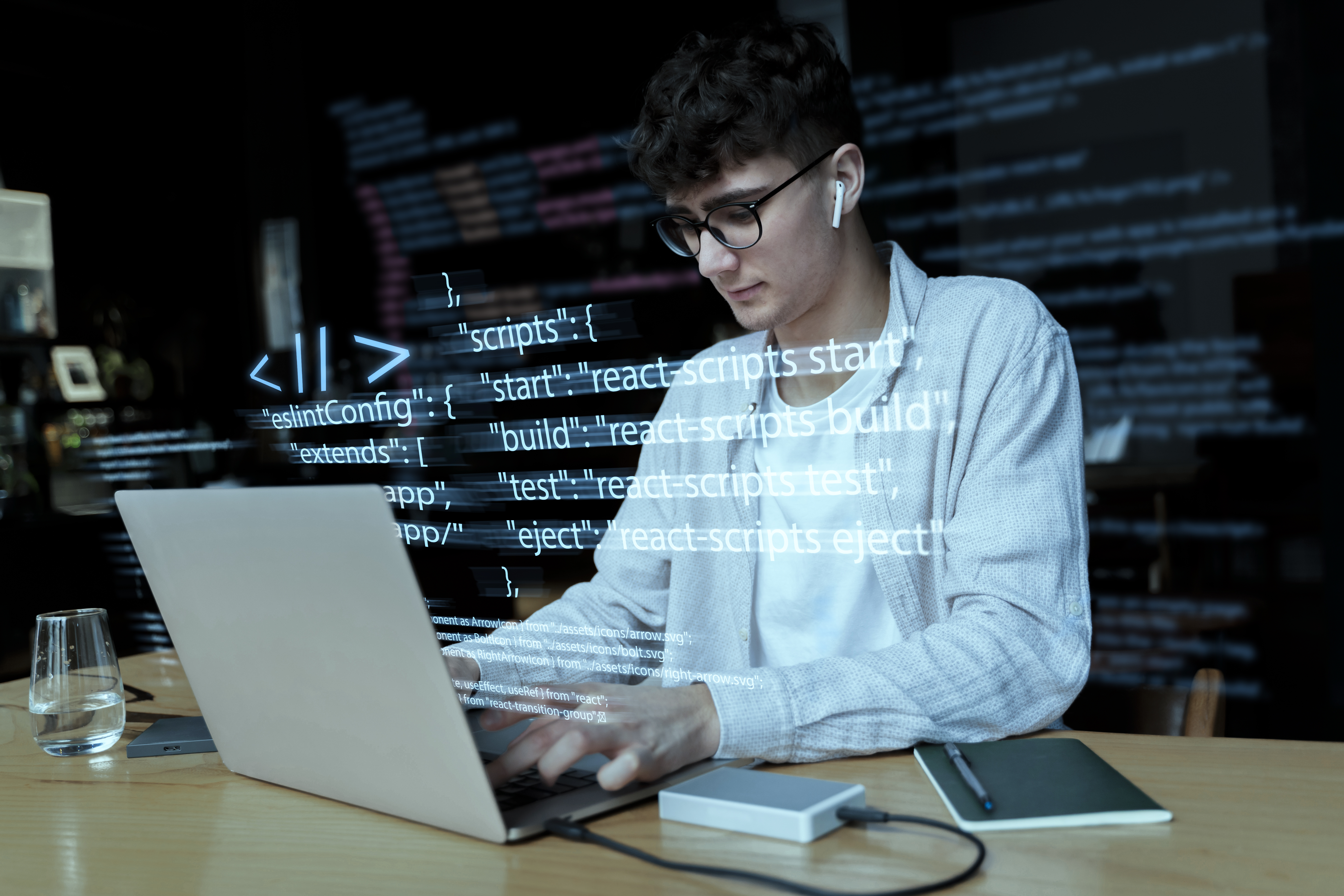 A young male programmer wearing glasses and earphones, working on a laptop with lines of code digitally overlaid on the image.